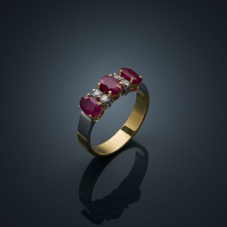 BAGUE en or jaune et or gris (750‰) serti de trois rubis ovales et de quatre di…