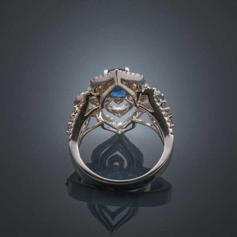 BAGUE "fleur stylisée" en or gris (750‰) ajouré, serti d'un saphir rond, entour…