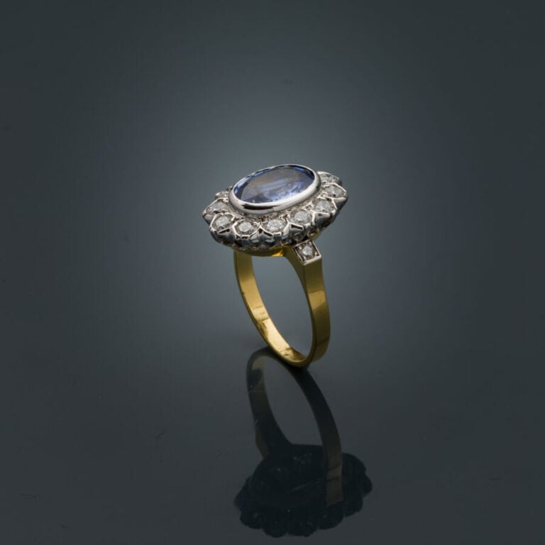 BAGUE "marguerite" en or jaune et or gris (750‰) serti d'un saphir ovale, entou…