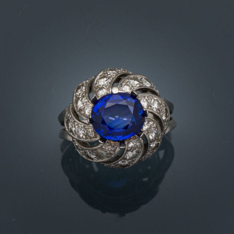 BAGUE "Tourbillon" en platine (950‰) ajouré, serti d'un saphir ovale, entouré d…