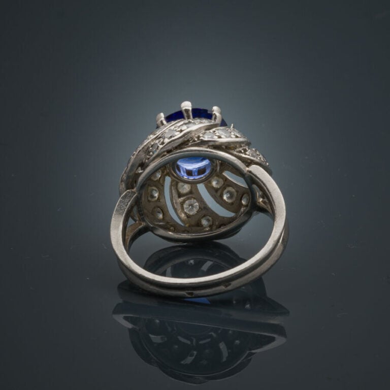 BAGUE "Tourbillon" en platine (950‰) ajouré, serti d'un saphir ovale, entouré d…