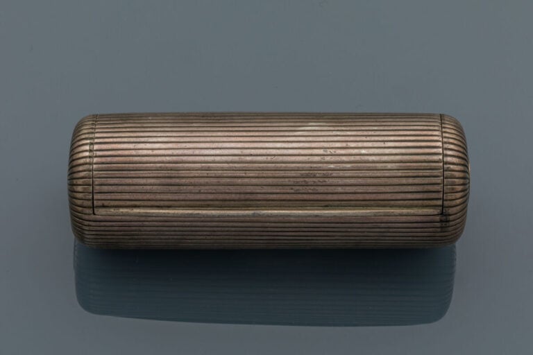 BOITE cylindrique en argent (min. 800‰) godronné, ouvrant à charnières. Intérie…