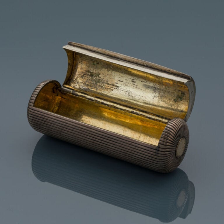 BOITE cylindrique en argent (min. 800‰) godronné, ouvrant à charnières. Intérie…