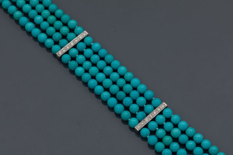 BRACELET composé de quatre rangs de perles de turquoises retenus par trois barr…