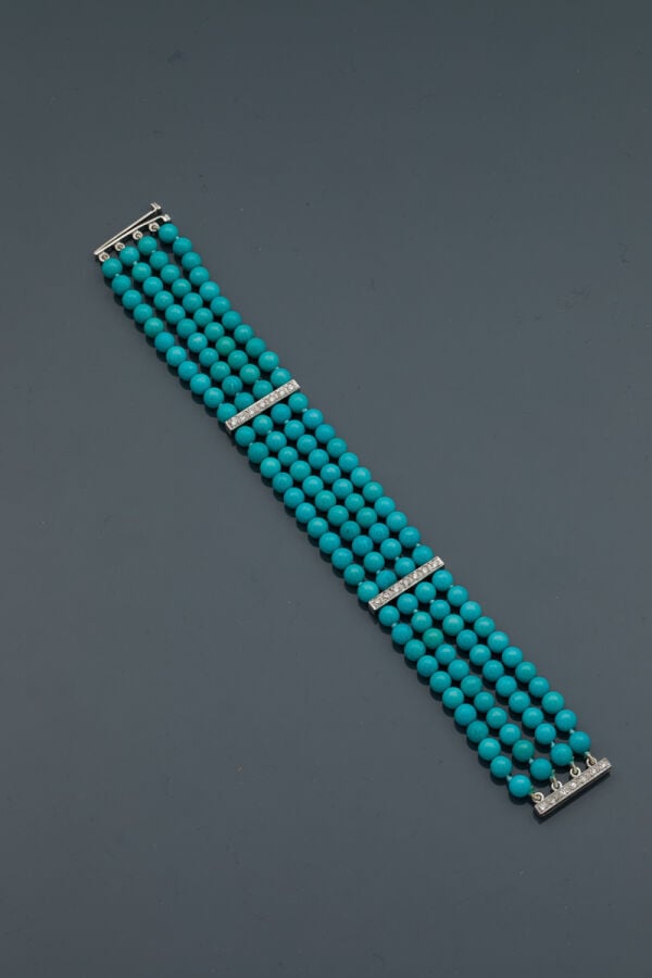 BRACELET composé de quatre rangs de perles de turquoises retenus par trois barr…