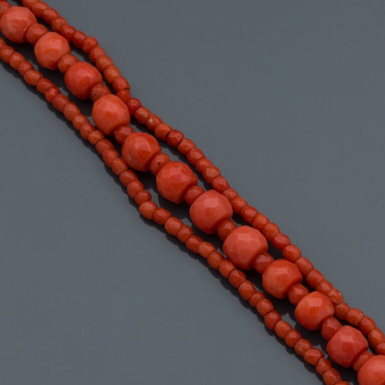BRACELET composé de trois rangs de perles de corail facetté. Fermoir en or jaun…