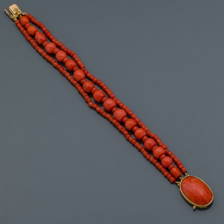 BRACELET composé de trois rangs de perles de corail facetté. Fermoir en or jaun…