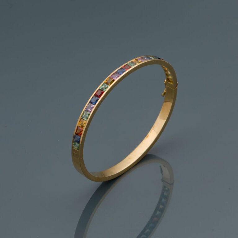 BRACELET "rainbow" rigide ouvrant en or jaune (750‰) serti d'un alignement de s…