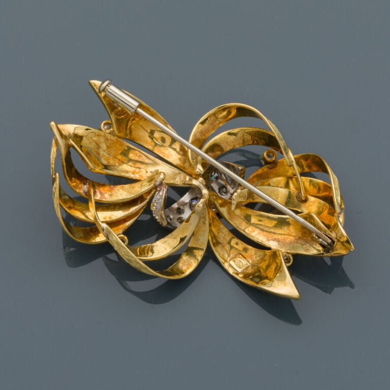 BROCHE "noeud" stylisé en or jaune et or gris (750‰) ajouré, ciselé et finement…