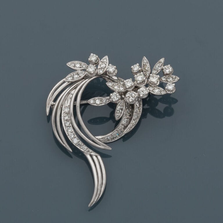 BROCHE "volutes et feuillages" en or gris (750‰) ajouré, serti de diamants tail…