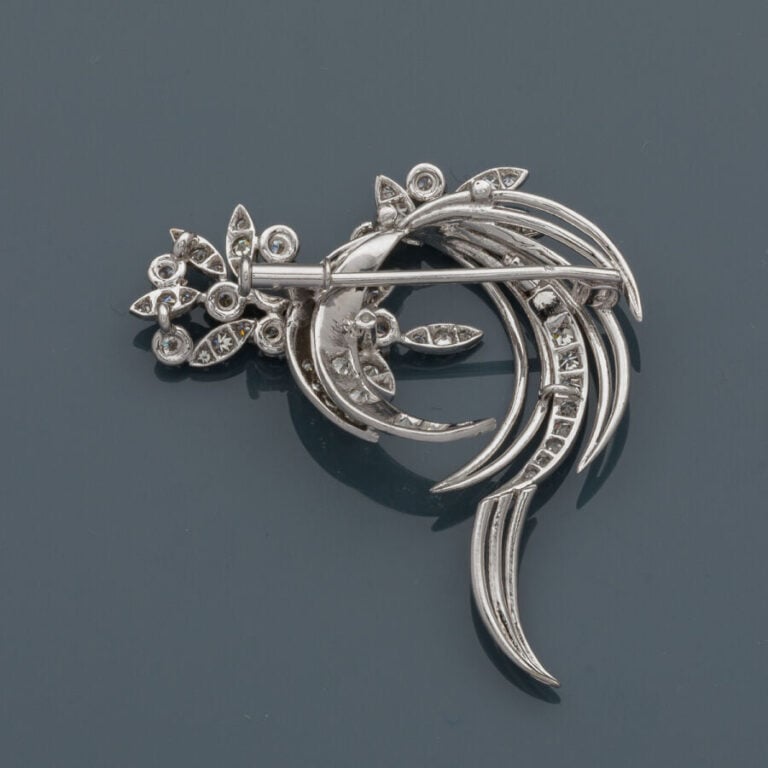 BROCHE "volutes et feuillages" en or gris (750‰) ajouré, serti de diamants tail…