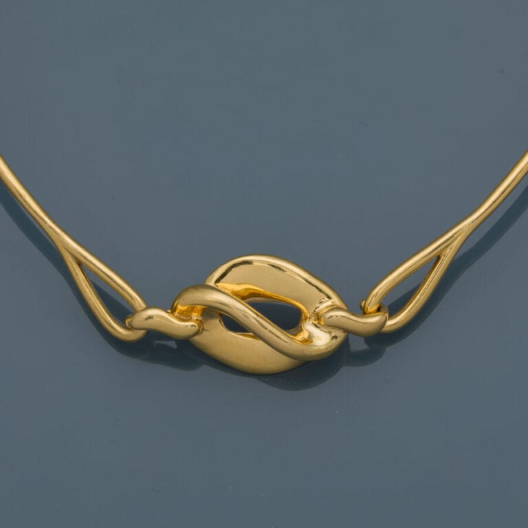 COLLIER "torque" en or jaune (750‰) centré d'un motif "volutes" ajouré. - Trava…
