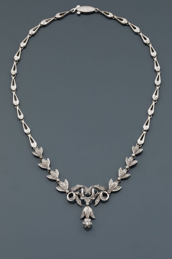COLLIER "volutes"en or gris (750‰) articulé et ajouré, serti de petits diamants…
