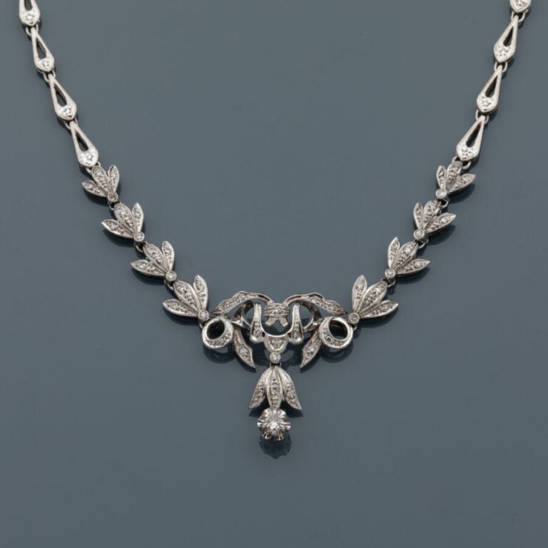 COLLIER "volutes"en or gris (750‰) articulé et ajouré, serti de petits diamants…