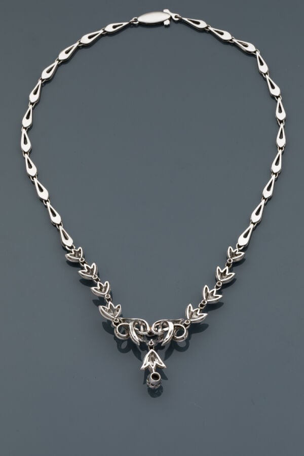COLLIER "volutes"en or gris (750‰) articulé et ajouré, serti de petits diamants…