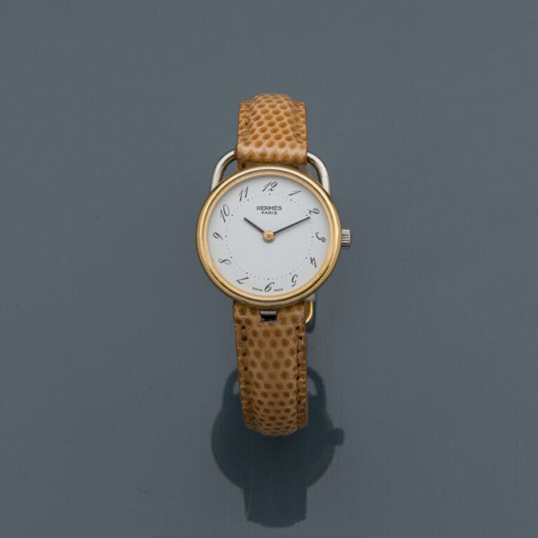 HERMES - BRACELET MONTRE ronde de dame, modèle "Arceau" en acier et métal doré.…