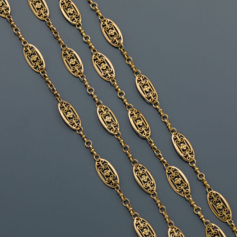 PAIRE de CHAINES ou long SAUTOIR en or jaune (750‰) à maillons ovales ajourés d…