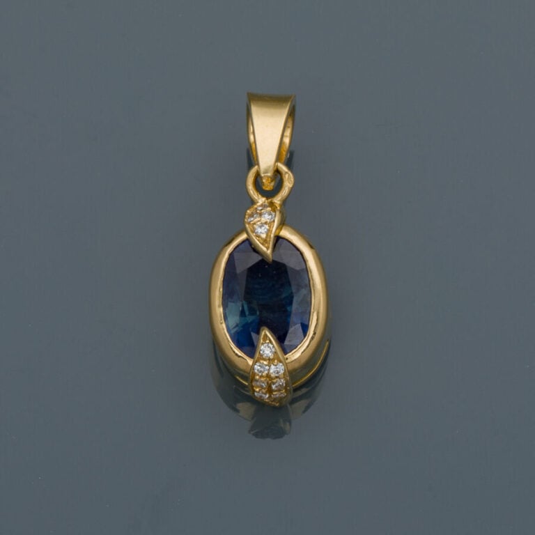 PENDENTIF en or jaune (750‰) serti d'un saphir de forme ovale épaulé de diamant…