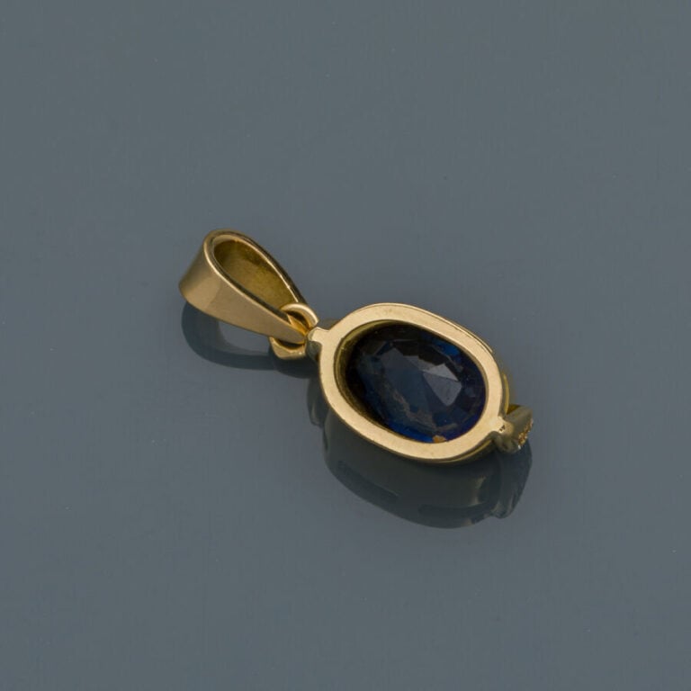 PENDENTIF en or jaune (750‰) serti d'un saphir de forme ovale épaulé de diamant…