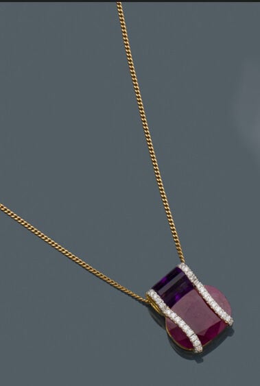 PENDENTIF géométrique et sa chaînette en or jaune (750‰) serti d'un rubis ovale…