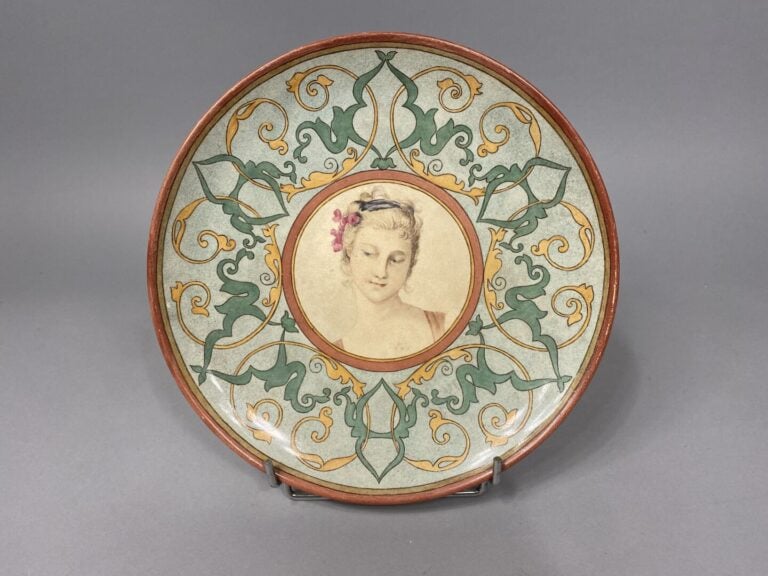 Assiette en faïence craquelée polychrome à décor de rinceaux et médaillon au po…