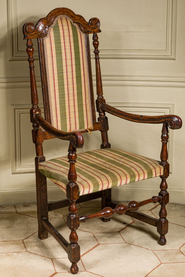 FAUTEUIL DU XVII SIECLE, en noyer mouluré et sculpté, le dossier flanqué de col…
