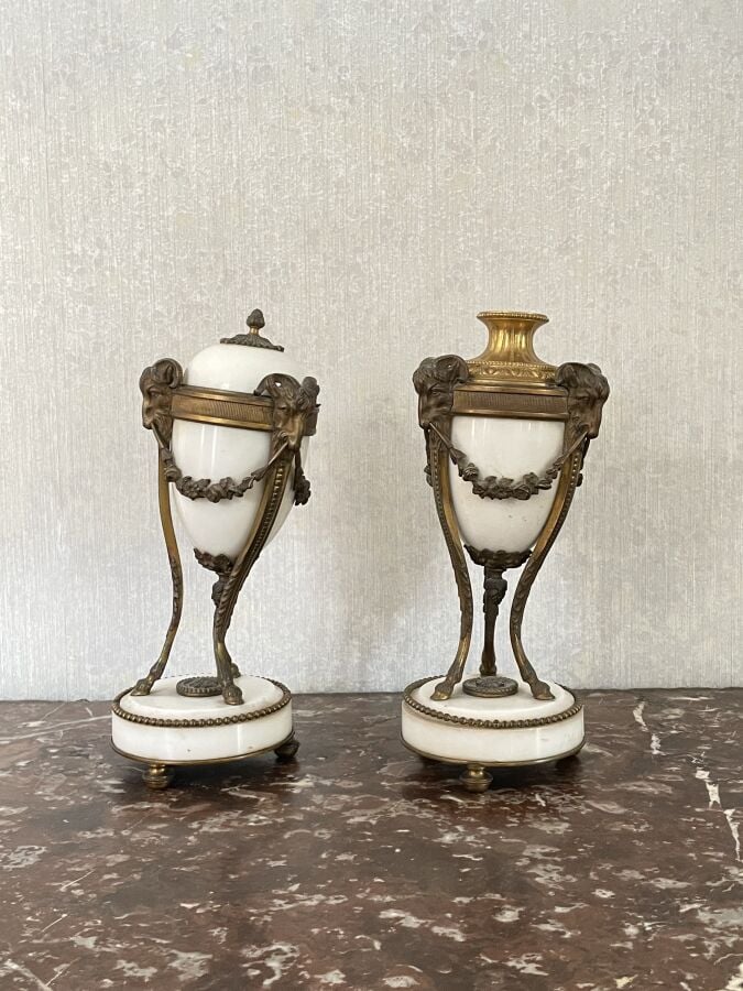 PAIRE DE CASSOLETTES en marbre blanc ; monture en bronze doré à têtes de bouque…