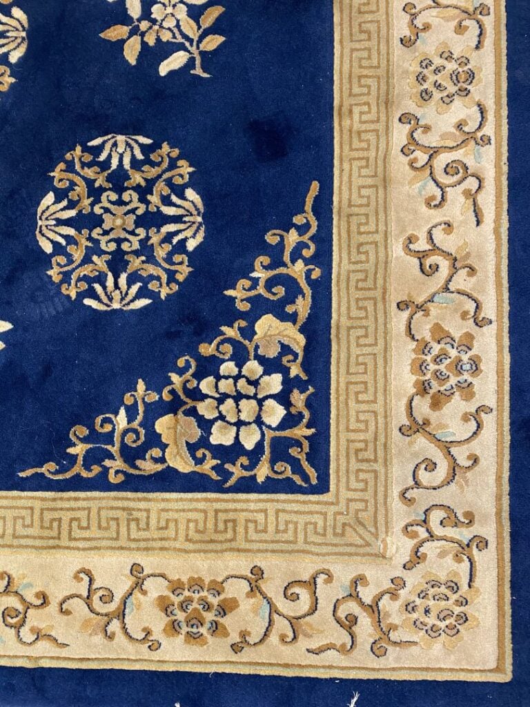 Tapis style chinois à décor floral sur fond bleu ceint d'une bordure dorée orné…
