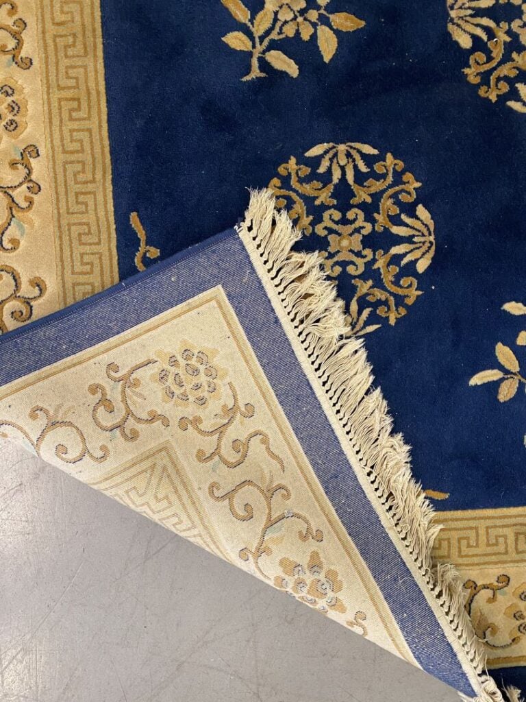 Tapis style chinois à décor floral sur fond bleu ceint d'une bordure dorée orné…