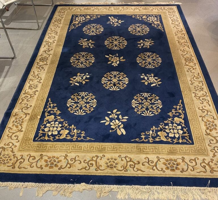 Tapis style chinois à décor floral sur fond bleu ceint d'une bordure dorée orné…