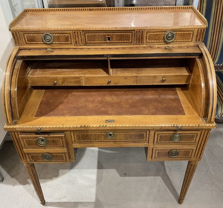 Bureau à cylindre à décor marqueté d'attributs. Le cylindre démasque trois tiro…