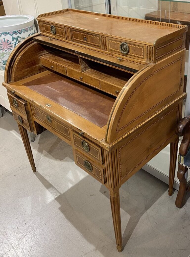 Bureau à cylindre à décor marqueté d'attributs. Le cylindre démasque trois tiro…