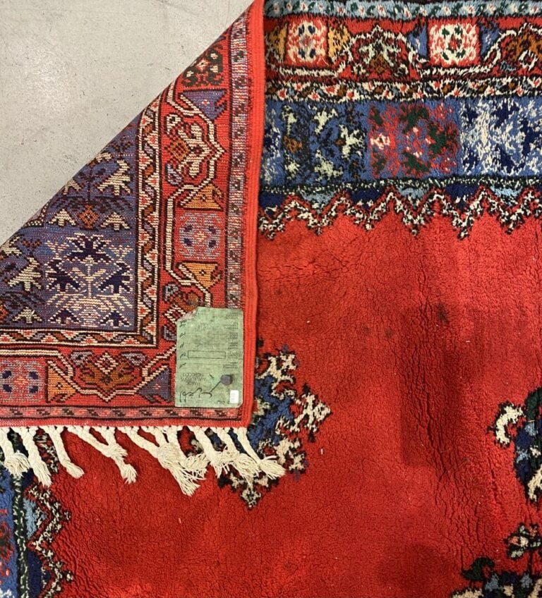 MAROC - Tapis en laine à fond rouge centré d'un motif floral, la bordure est so…