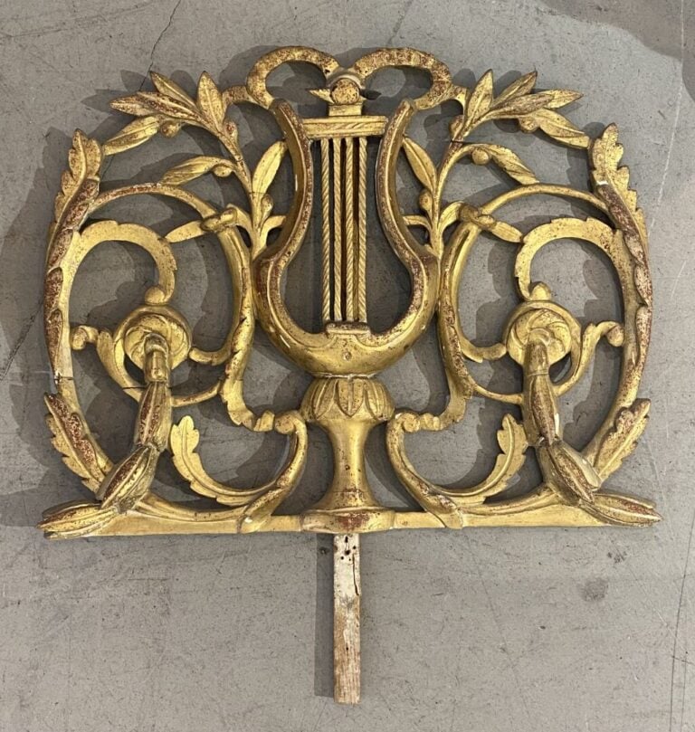 Miroir en bois doré surmonté d'un fronton ajouré orné d'une lyre et enroulement…