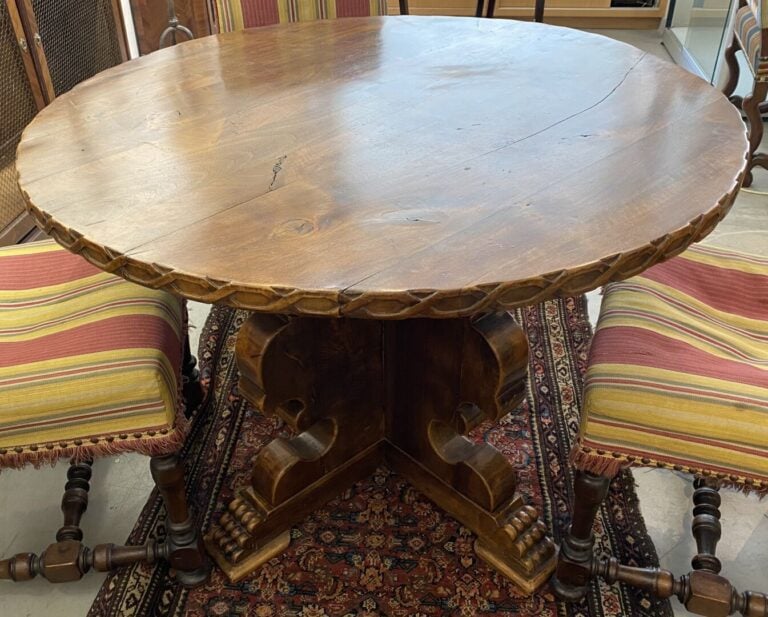 Table en bois à plateau rond, le piétement découpé terminé par des pieds griffe…