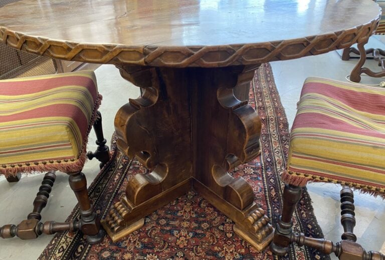Table en bois à plateau rond, le piétement découpé terminé par des pieds griffe…