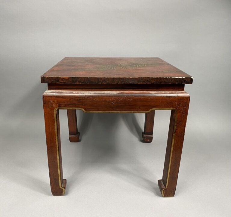 Chine - Petite table basse en bois laqué rouge à décor doré d'un village entour…