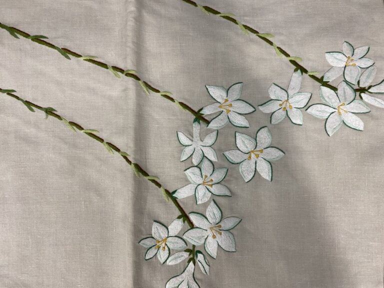 Ensemble de deux nappes en toile beige à décor de fleurs blanches
