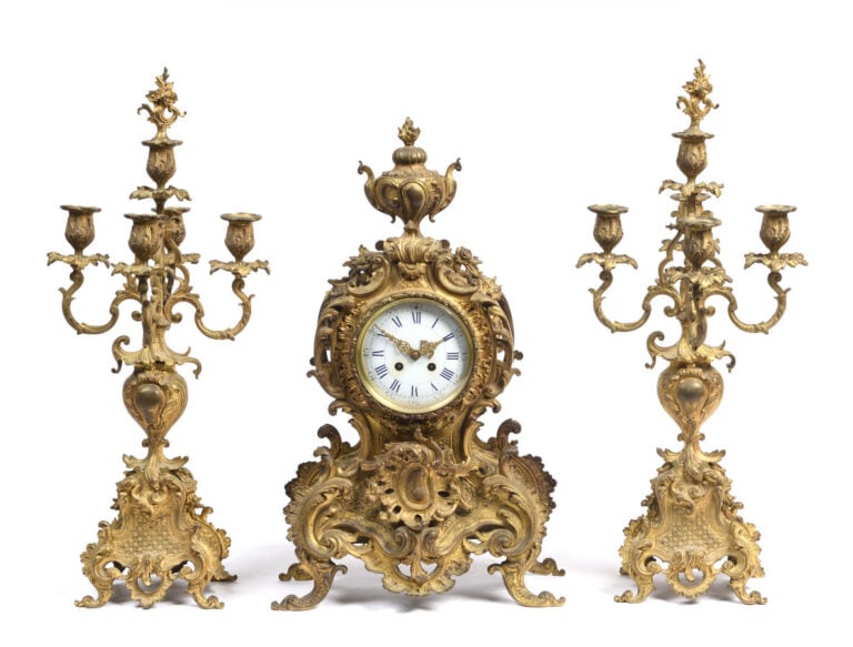 Garniture de cheminée. Pendule en bronze doré à décor rocaille sommé d'un vase.…