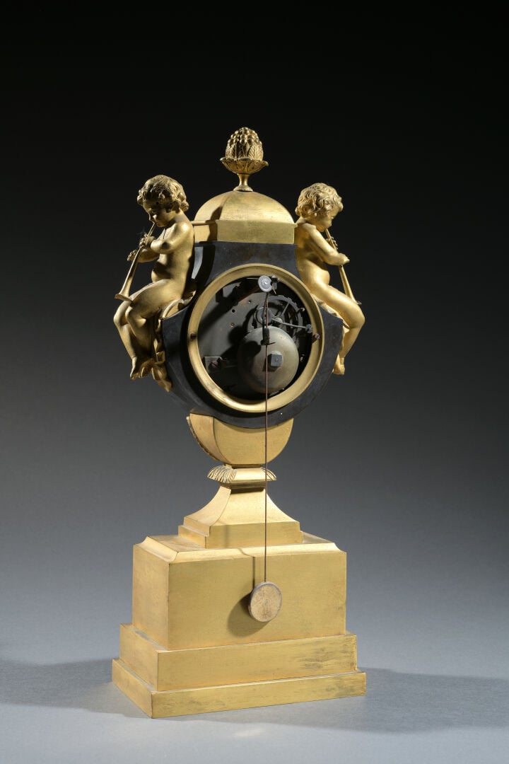 Pendule vase en bronze à double patine brune et dorée, le cadran surmonté d'une…