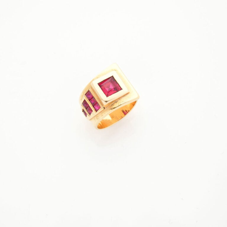 BAGUE asymétrique en or jaune (750‰) orné de pierres rouges synthétiques calibr…