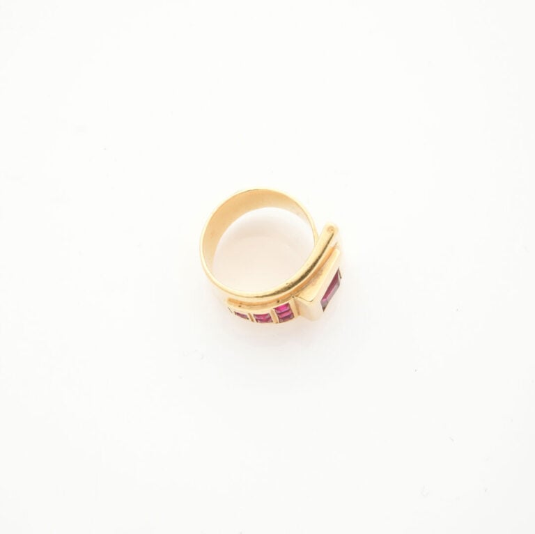 BAGUE asymétrique en or jaune (750‰) orné de pierres rouges synthétiques calibr…