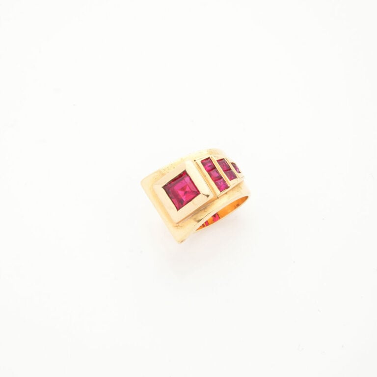BAGUE asymétrique en or jaune (750‰) orné de pierres rouges synthétiques calibr…