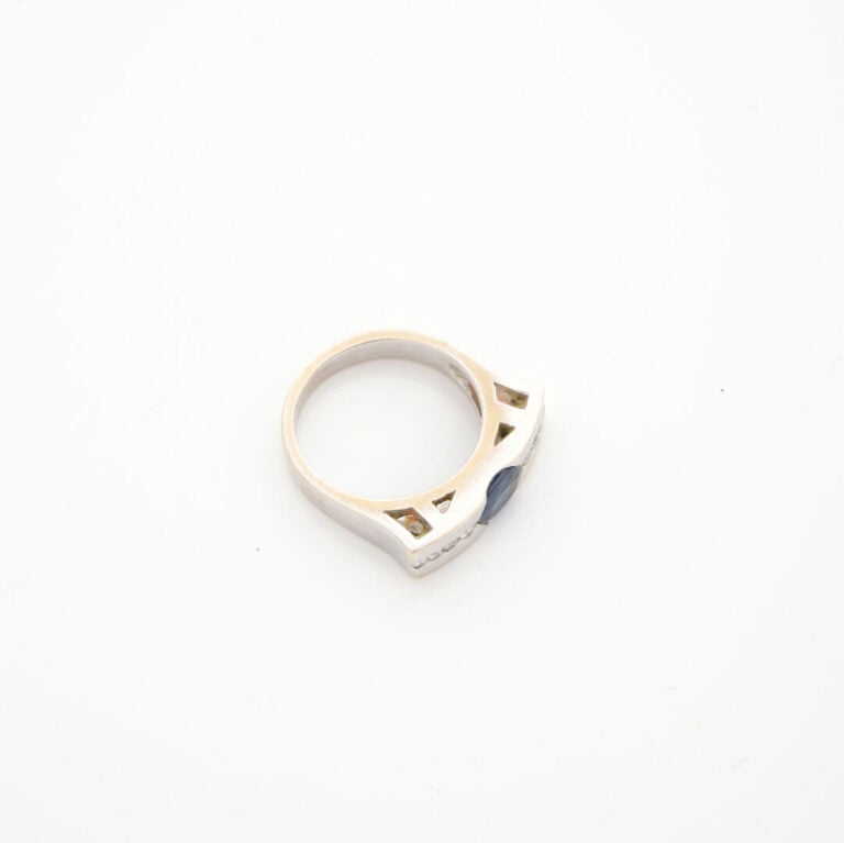 BAGUE "barrette" en or gris (750‰) centré d'un saphir de forme ovale, épaulé d'…