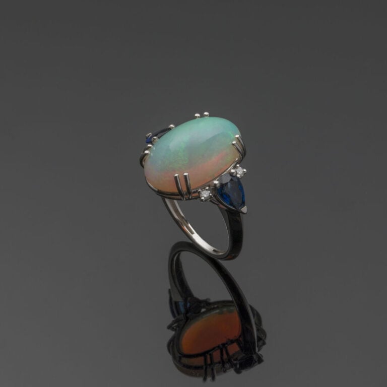 BAGUE en or gris (750‰) orné d'une opale cabochon épaulée de chaque côté d'un s…