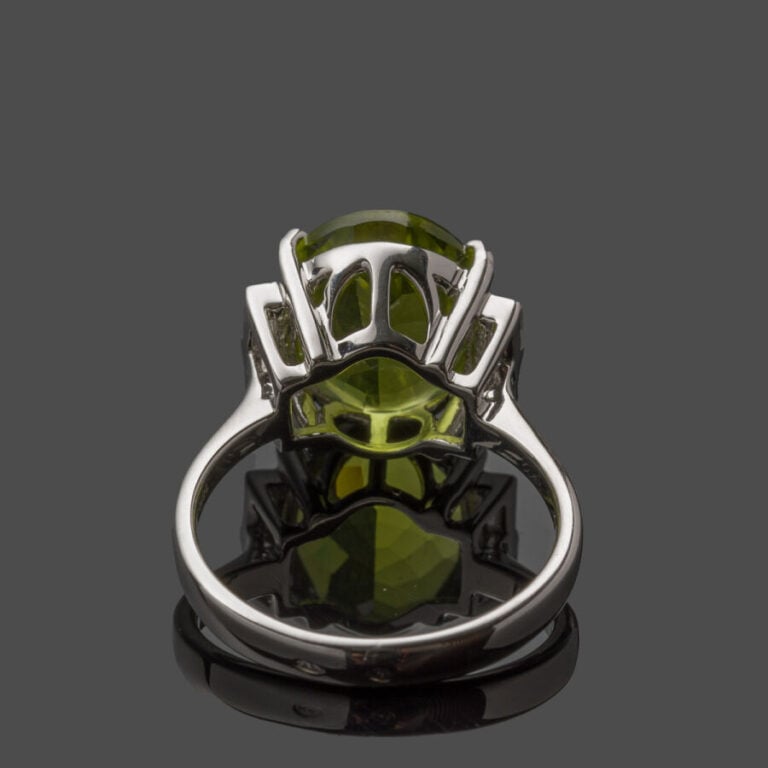 BAGUE en or gris (750‰) serti d'un péridot ovale, épaulé de quatre diamants tai…