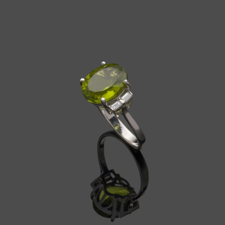 BAGUE en or gris (750‰) serti d'un péridot ovale, épaulé de quatre diamants tai…