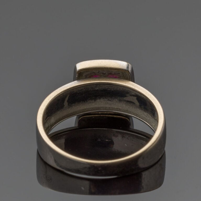BAGUE jonc plat en or gris (750‰) centrée d'un motif carré serti de quatre rubi…