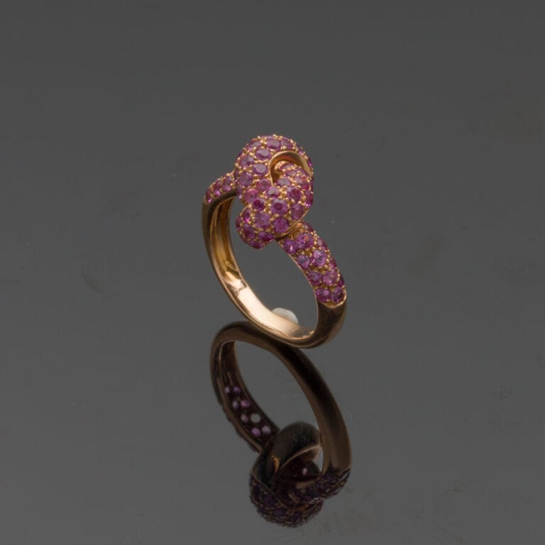 BAGUE "noeud" en or rose (750‰) serti de saphirs roses. Manque une pierre. - Do…