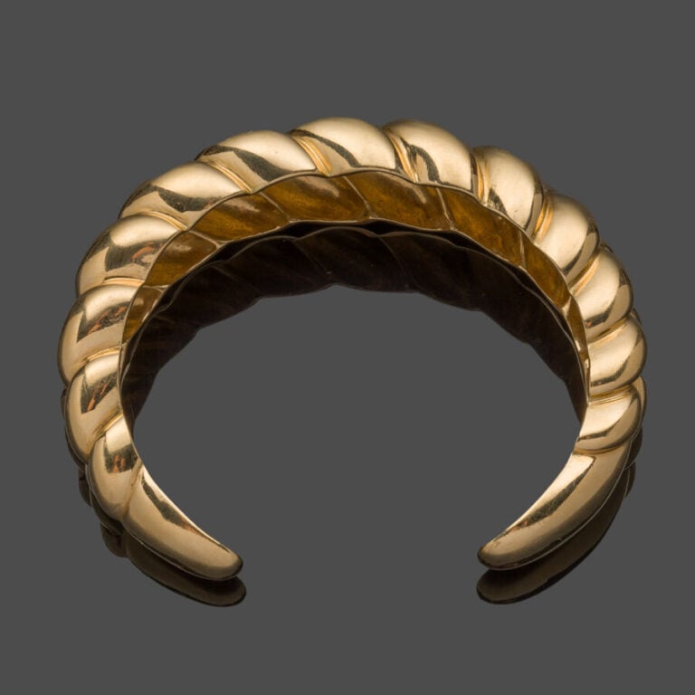 BRACELET rigide ouvert en or jaune (750‰) godronné à motif de tresse légèrement…